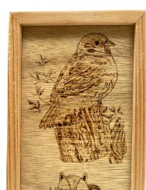 Close-up of a detailed pyrography bird perched on a tree stump.