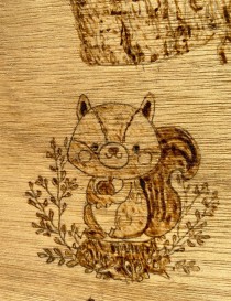 Close-up of a whimsical squirrel holding an acorn in a woodburned style.