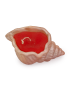 Overhead view of pink seashell concrete candle with red wax and wick.