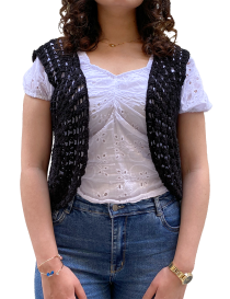 Front view of a model wearing a black handmade crochet vest with blue jeans.