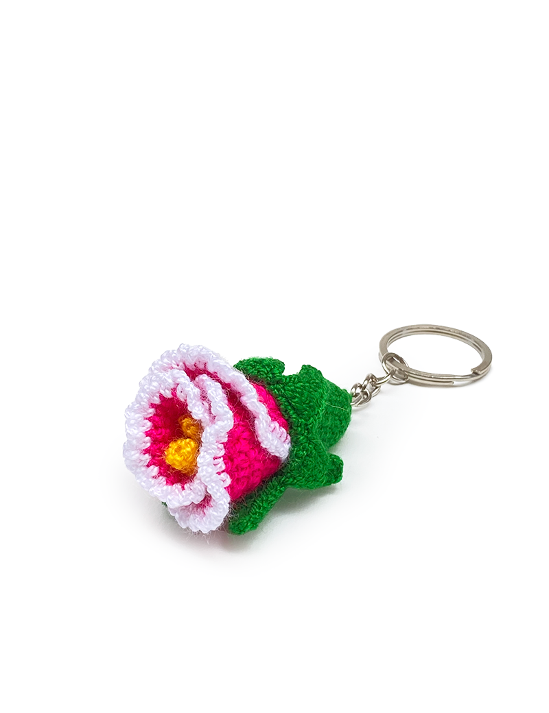 Angled view of a pink and white crochet flower keychain with metal ring.