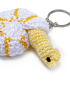 Macro view of white and yellow handmade crochet snail keychain.