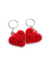 Two red amigurumi heart keychains with embroidered smiles and pearl accents.