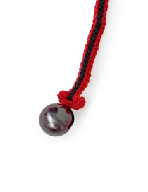 Close-up of a dark polished bead attached to a red and black crochet bookmark stem.