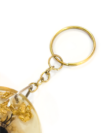 Close-up of a gold-tone metal keychain ring and chain attached to a resin pendant.