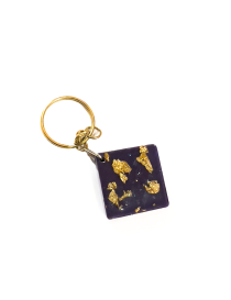 Square black resin keychain with shimmering gold leaf flakes and gold-tone metal ring.