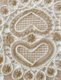 Close-up of beige cotton lace and white ribbon heart detail.