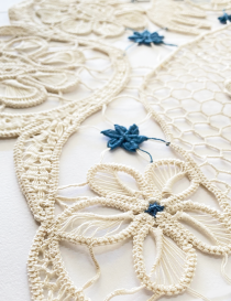 Close-up of the woven floral lace motifs and blue thread accents.