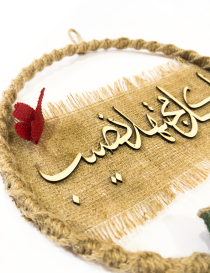 Close-up of wooden Arabic calligraphy on burlap background.