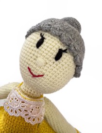 Close-up of a handmade crochet doll with grey hair bun and lace collar.