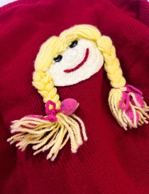 Closeup to handmade red knitted cardigan for girls with buttons and ribbed collar. Girl face.
