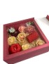 Crimson red wooden gift box with sliding glass lid containing floral-shaped wax candles.