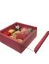 Crimson red wooden gift box with sliding glass lid containing floral-shaped wax candles.