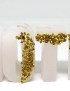 White wax letter candles with gold glitter accents spelling out a word on a white surface.