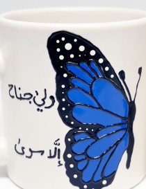 Pair of white ceramic mugs with a blue butterfly design and Arabic calligraphy.