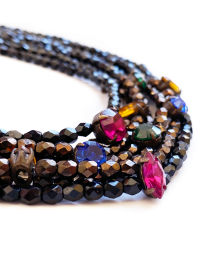 Macro shot of pink, blue, and green crystals on black faceted beads.