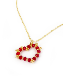 Overhead view of red beaded heart necklace on a white background.