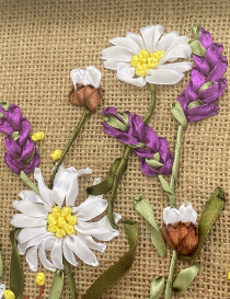 Detailed shot of handcrafted white daisies and purple lavender ribbon embroidery.