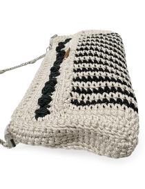 Perspective view of a beige and black crochet handbag showing textured stitching.
